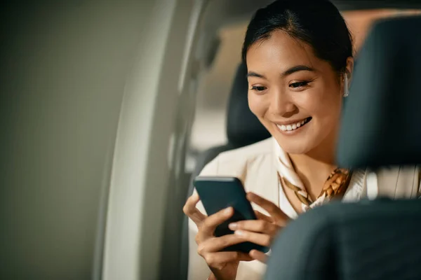 Happy Asian Female Ceo Text Messaging Mobile Phone Sitting Backseat — Foto Stock