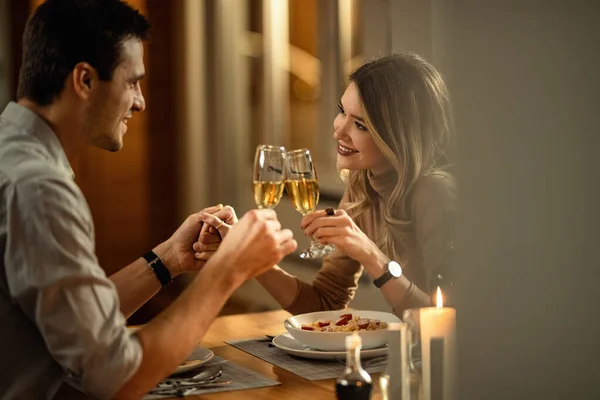 Young Happy Couple Toasting Champagne While Holding Hands Having Dinner — стоковое фото