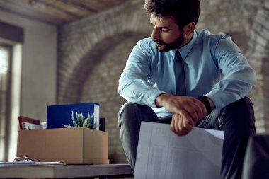 Young distraught businessman thinking of something in the office after getting fired from his job. 