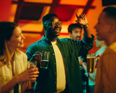 Cheerful African American man having fun with his friends during the night out in a bar. 