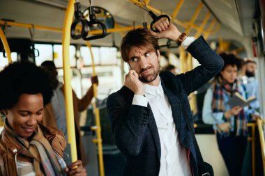 Distraught businessman talking on the phone while traveling to work by public transport. 