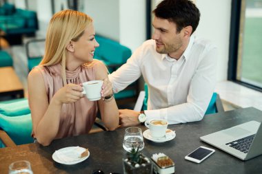 Happy business colleagues communicating while enjoying on coffee break in a cafe. 