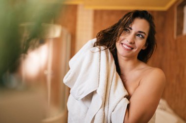 Beautiful smiling woman drying her hair with a towel in the bathroom.