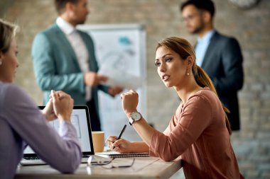 Young businesswoman talking to her female colleague during the meeting in the office. 