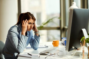 Young pensive businesswoman having a headache while having some problems at work. 