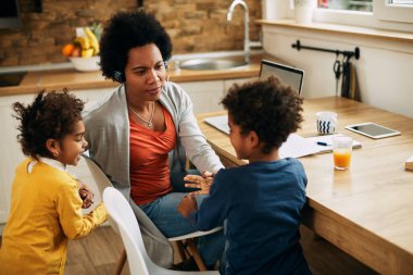African American mother separates her mischievous children she is working at home.