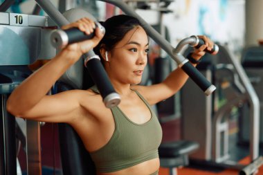 Spor salonunda egzersiz yaparken göğüs egzersizi yapan genç Asyalı atletik kadın..
