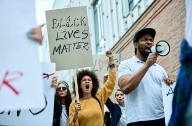 Low angle view of multi-ethnic group of people shouting on public demonstrations against racism. 