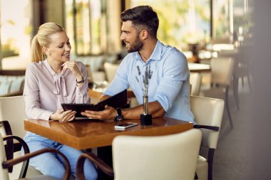 Happy couple enjoying while choosing an order from menu in a cafe.  