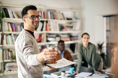 Happy businessman giving presentation to his coworkers while working on new creative project in the office.