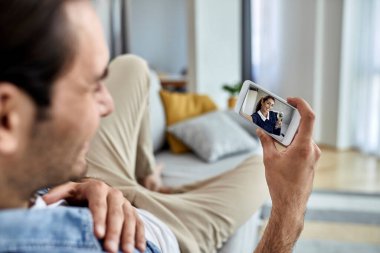 Akıllı telefon kullanan ve evden kız arkadaşıyla online randevuya çıkan bir adamın yakın çekimi. Dokunmatik ekrandaki kadına odaklan.. 