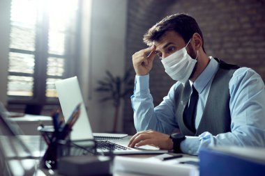 Young businessman reading problematic e-mail on laptop while working in the office. 