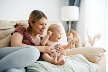 Young happy mother and her joyful baby boy enjoying in time together at home. 