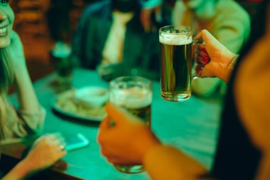 Close-up of waitress giving beer to guests in a pub at night. 