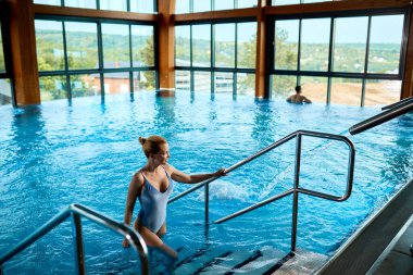 High angle view of a woman getting out of the water after swimming in the pool at the spa. Copy space.