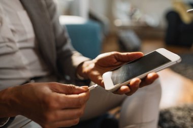 Close-up of black businesswoman plugging mobile phone to USB charger.