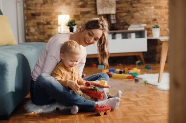 Happy m other and son having fun while playing on the floor at home.