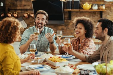 Group of young people having fun and toasting with wine during lunch time at home. 