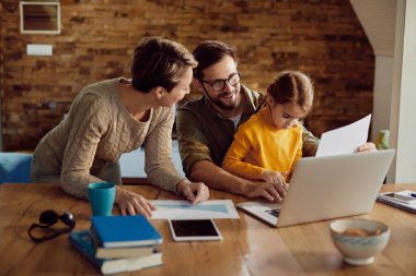 Happy father using computer with his family while working at home.
