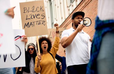 Low angle view of multi-ethnic group of people supporting Black Lives Matter movement and protesting on city streets. 
