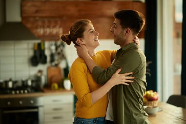 Happy couple in love communicating while standing embraced at home. 