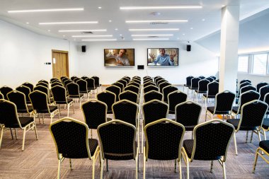 Two businessmen giving a presentation via projection screen in conference room with no people. 