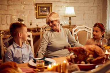 Happy grandmother and grandchildren communicating while having a meal on Thanksgiving.