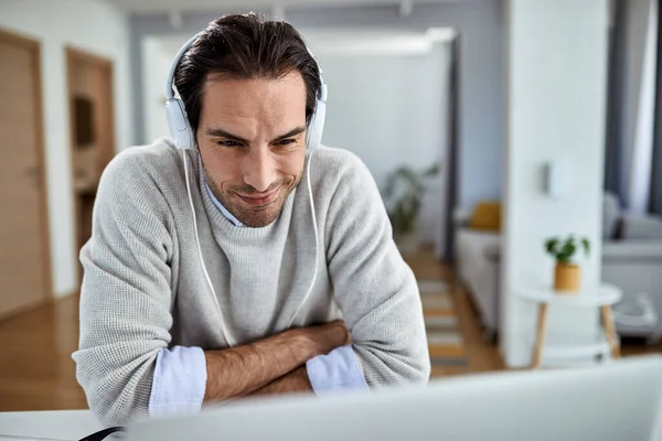 Young Smiling Businessman Headphones Reading Something Computer While Working Home — Stockfoto