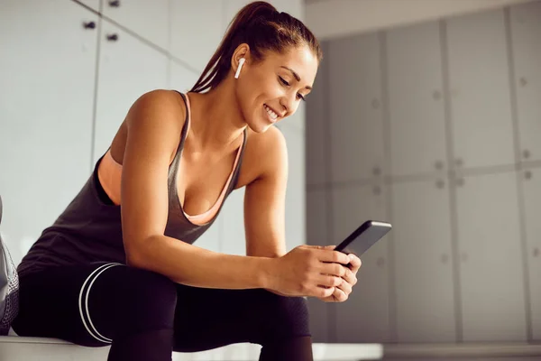 Young Athletic Woman Using Smart Phone Text Messaging Locker Room — Stockfoto