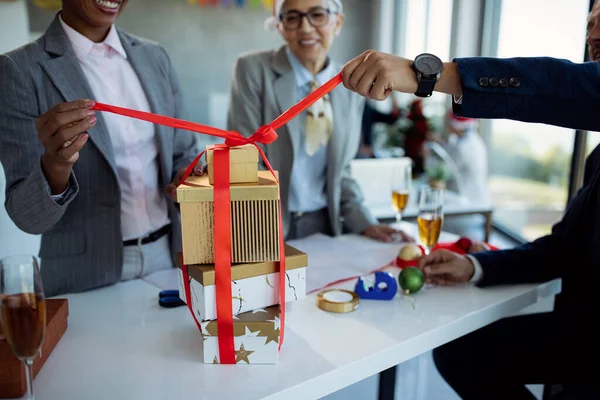 Close-up of business people opening gift boxes while celebrating Christmas at office party.