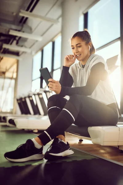 Young Sportswoman Using Smart Phone While Taking Break Exercising Gym — Stockfoto
