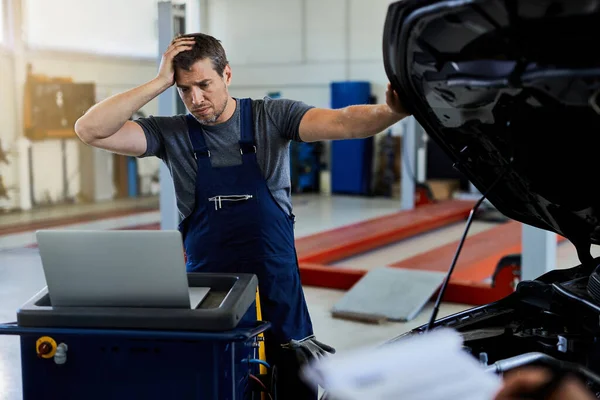 Distraught Mechanic Having Problems While Repairing Car Engine Using Laptop — Fotografia de Stock