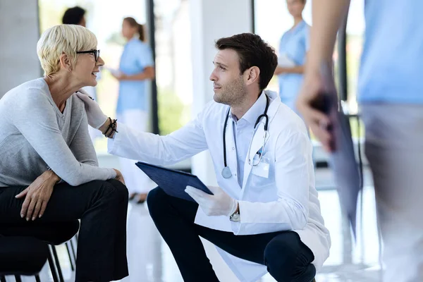 Male Doctor Consoling Senior Woman While Talking Her Waiting Room — Foto Stock