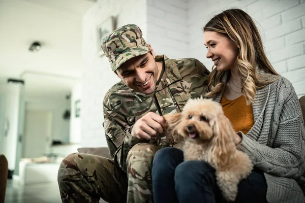 Young happy military officer having fun with his wife and dog after coming home from an assignment.