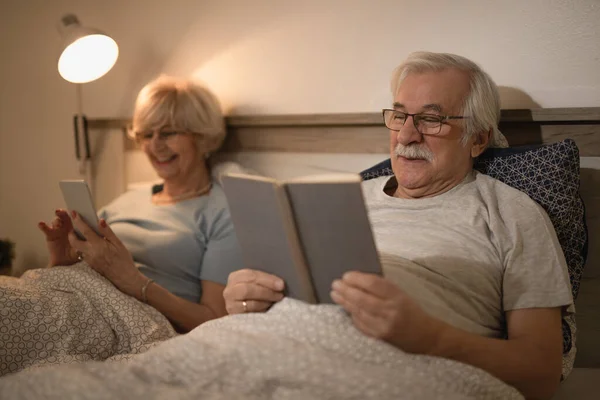 Smiling Mature Man Lying Bed Reading Book While His Wife — Photo