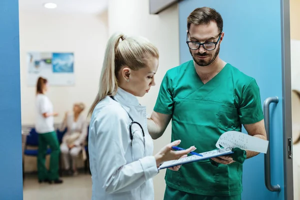 Two Doctors Analyzing Medical Reports While Standing Lobby Clinic Focus — Foto Stock