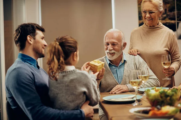 Happy Senior Man Receiving Gift His Granddaughter Family Lunch — Foto Stock