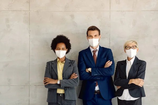 Small group of happy business people feeling confident while standing  with arms crossed and wearing face masks due to COVID-19 pandemic. Copy space.