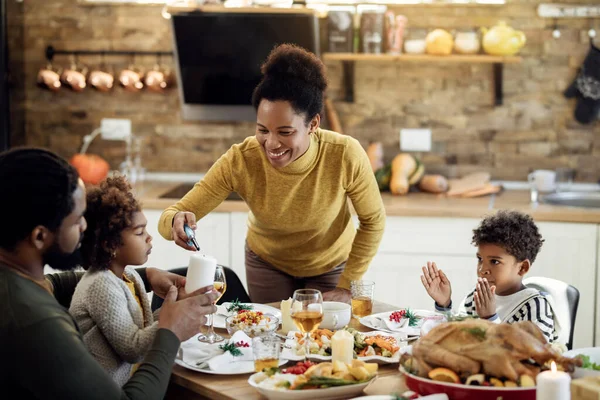 Happy black woman lightening candle while having family lunch on Christmas day at home.
