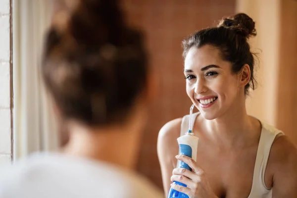 Молода Щаслива Жінка Використовує Флосер Стоматологічної Води Прибираючи Зуби Дивлячись — стокове фото