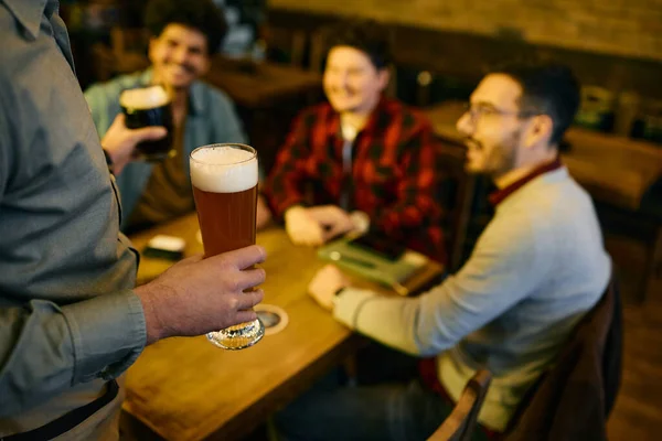 Close up of waiter serving beer to customers while working in a bar.