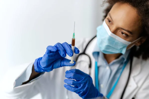 Close-up of African American doctor testing antiviral drug in the hospital.