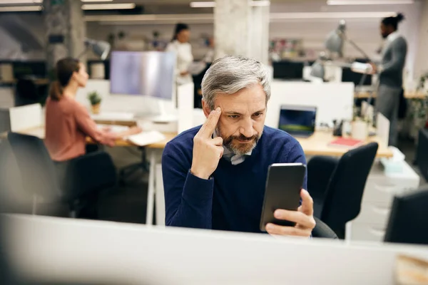 Mature Businessman Reading Problematic Text Message Mobile Phone While Working — Stock Fotó