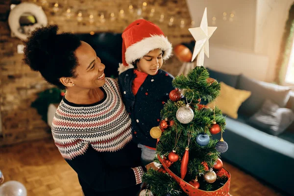 Happy Black Mother Holding Her Small Daughter While Decorating Christmas — ストック写真