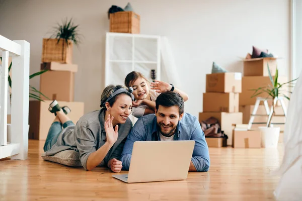 Happy family using laptop and greeting someone after moving into their new home.