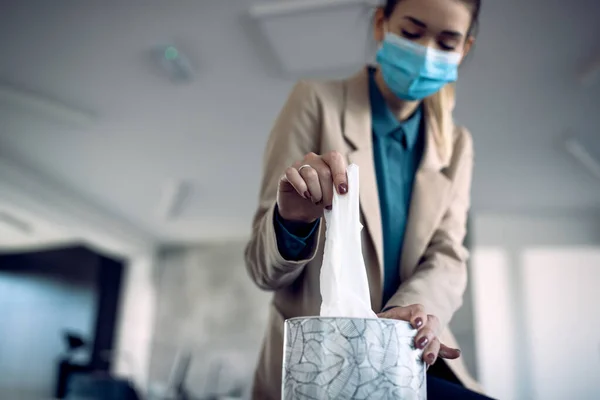 Close-up of businesswoman taking a tissue from the box in the office during COVID-19 pandemic.