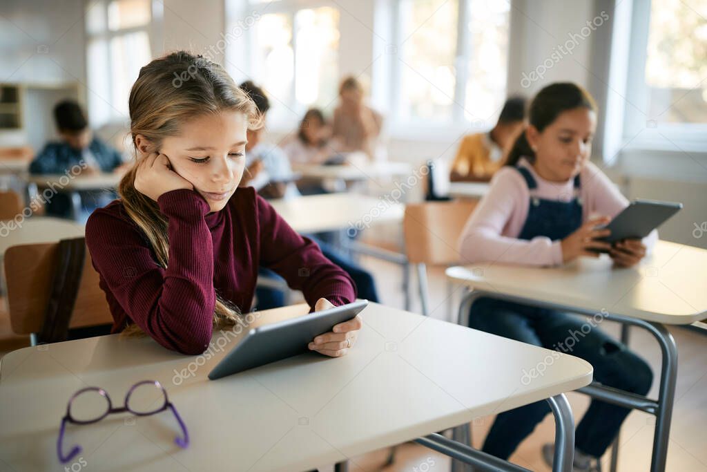Schoolgirl reading on digital tablet in the classroom at primary school. 