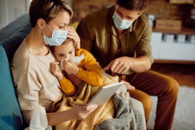 Caring parents communicating about daughter's medical condition with a  doctor via video call during coronavirus pandemic.
