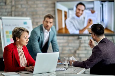 Female entrepreneur using laptop while having business video conference meeting in the office. 