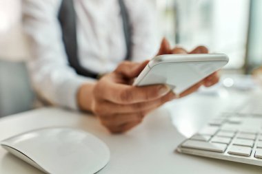 Close-up of businesswoman using smart phone and text messaging in the office. 